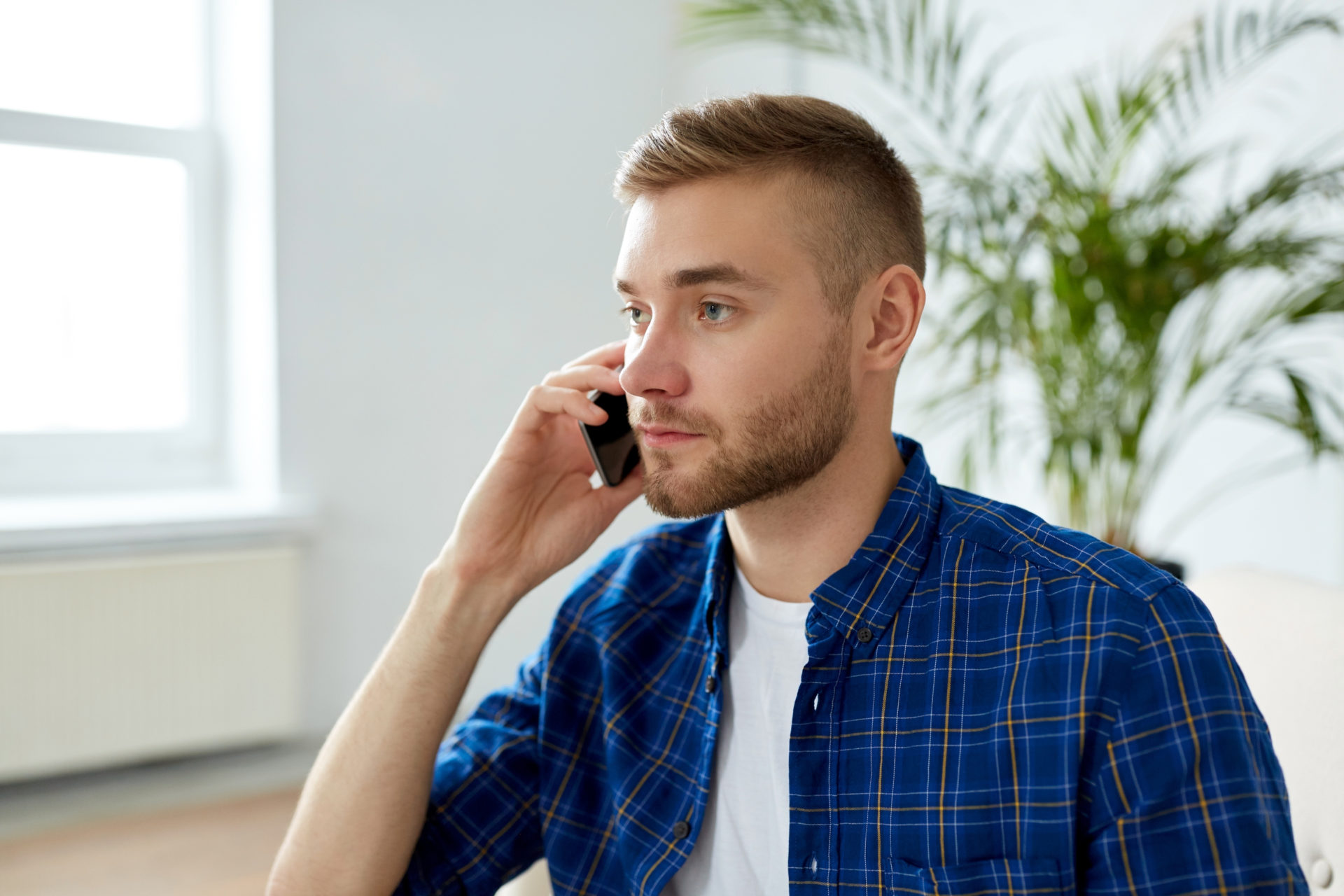 smiling young man calling on smartphone at office